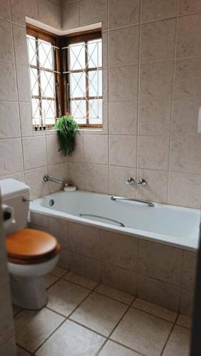 a bathroom with a toilet and a bath tub with a toilet at Mkababa's beautiful and spacious in Durban