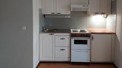 a kitchen with white cabinets and a stove top oven at Arantilan rivitalokaksio in Nakkila