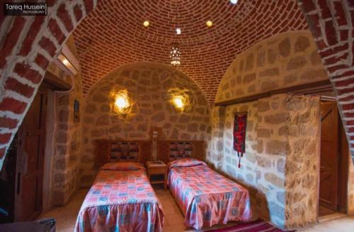 a room with two beds in a stone wall at Aliyah Eco-Lodge in Bawati