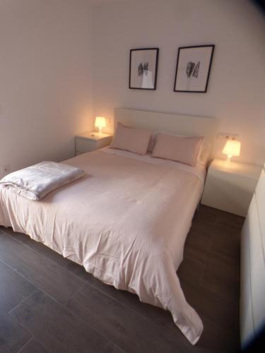 a bedroom with a large white bed with two lamps at Pis pràctic i agradable sobre la Marina Palamós in Palamós