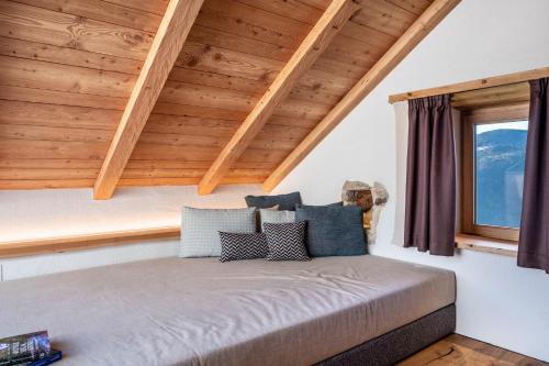 a bed in a room with wooden ceilings at Spornberg Mountain Living Nordberg in Soprabolzano