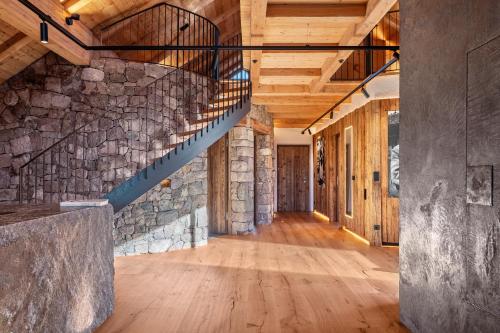 an empty hallway with a stone wall and wooden ceilings at Spornberg Mountain Living Nordberg in Soprabolzano