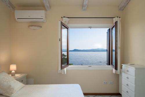ゴルフォ・アランチにあるVilla Mimosa con piscinaのベッドルーム1室(水辺の景色を望む窓付)