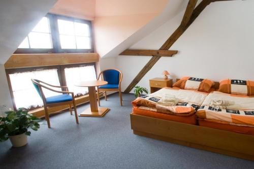 a bedroom with a bed and a table and chairs at Pension Smetanuv statek in Hradec Králové