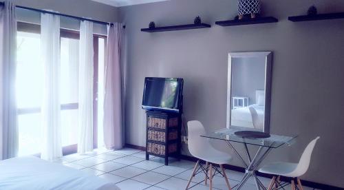a bedroom with a tv and a table and chairs at Samtip Sunset in Johannesburg