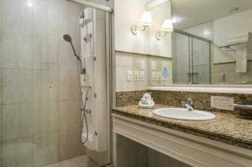 uma casa de banho com um lavatório e um chuveiro com um espelho. em IL Campanario - Suíte em Florianópolis