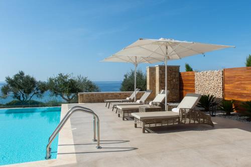 un grupo de sillas y una sombrilla junto a la piscina en Katergo Luxury Villas, en Stoupa