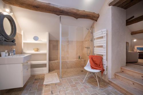uma casa de banho com um chuveiro, um lavatório e uma cadeira. em Clos Saint Jacques - Maison d'Hôtes em Meursault