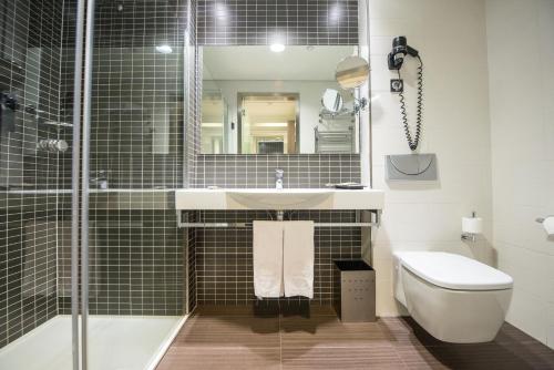 a bathroom with a sink and a toilet and a mirror at Axor Feria in Madrid