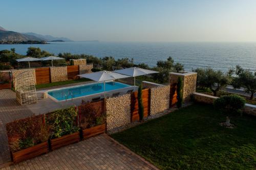 a swimming pool with umbrellas and the ocean at Katergo Luxury Villas in Stoupa