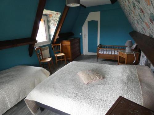 - une chambre avec 2 lits et un mur bleu dans l'établissement Gîte des Bois Rimbert, à Beuzeville