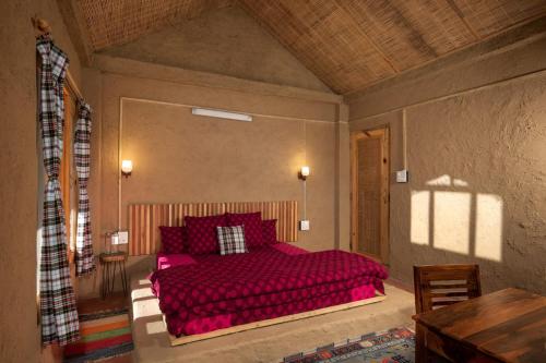 a bedroom with a large red bed with red pillows at Living Good - A Himalayan Boutique Stay in Gushaini