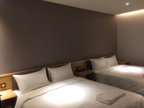 a hotel room with two beds with white pillows at Michi Hotel - Zhongli in Zhongli