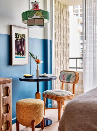 a bedroom with a bed and a table and chairs at Wayfinder Waikiki - Voted Top 10 Best Hotels in Hawaii! in Honolulu