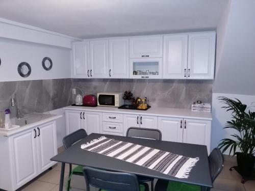 a kitchen with white cabinets and a table and chairs at Casa Nobilis in Gura Humorului