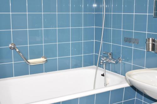 baño de azulejos azules con lavabo y bañera en Allod (166 Da) Whg. Nr. 103, en Lenzerheide