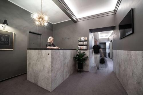 a woman standing at a counter in a lobby at The Viaduct - Suites & More in Prague