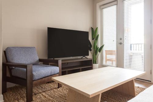 a living room with a tv and a chair and a table at Kasa FreeMoreWest Charlotte in Charlotte