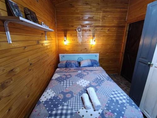 1 dormitorio pequeño con 1 cama en una habitación de madera en Cabaña El Ceibo en Puerto Iguazú