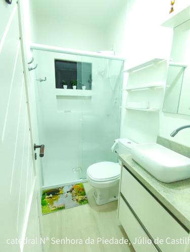 a white bathroom with a toilet and a sink at Residencial Privilegio in Florianópolis