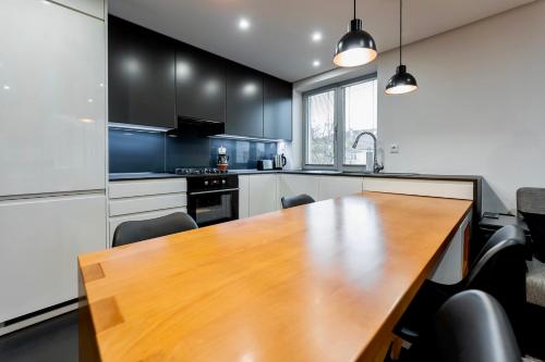 a kitchen with a wooden table and black cabinets at Luxury Apartment in the City Centre in Košice