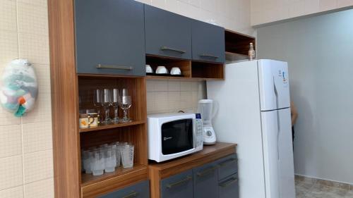 cocina con nevera blanca y microondas en Lindo Apartamento Pé na Areia Canto do Forte en Solemar