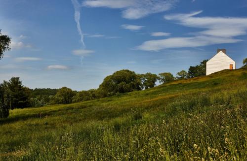 a white barn on top of a grassy hill at Inness in Accord