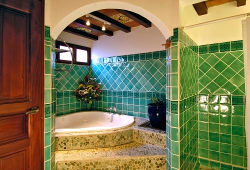 a green tiled bathroom with a tub and a sink at Hotel Colonial Granada in Granada