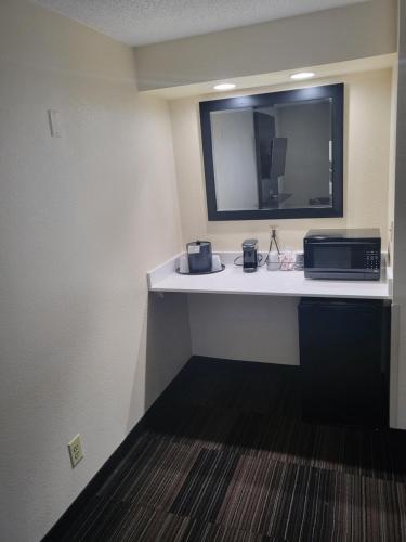 a room with a desk with a microwave and a mirror at Club Hotel Nashville Inn & Suites in Nashville