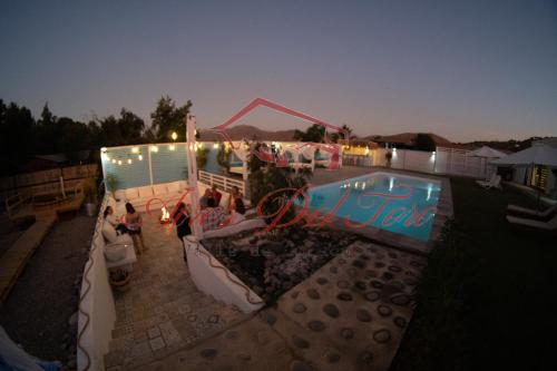 a group of people sitting around a pool at night at Cabañas Boutique Aires del Toro, Curacaví in Curacaví