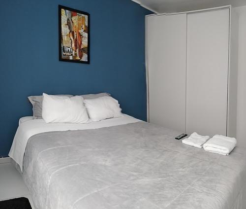 a bedroom with a large white bed with a blue wall at Gerard House Huancayo in Huancayo