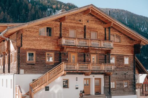 a log house with a balcony and a deck at Appartements Höllhaus in Innervillgraten