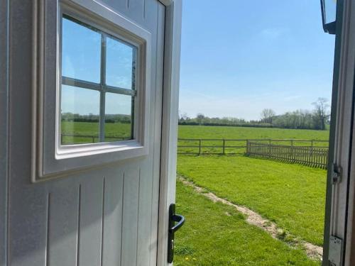 una porta con una finestra che guarda fuori un campo di Shepherd Hut a Warwick