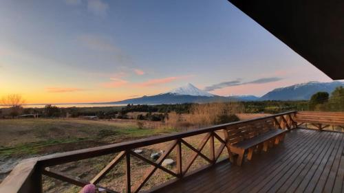 a bench on a deck with a mountain in the background at Moon River Puerto Varas in Puerto Varas