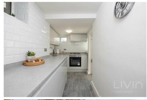 a white kitchen with a clock on the wall at Lovely 1 Bedroom Apartment in South Norwood
