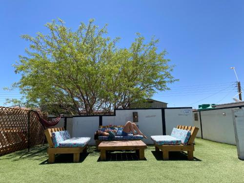 a person laying on a couch on a patio with two chairs at Rey Lagarto Hostel in San Pedro de Atacama
