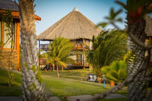a building with a straw roof and palm trees at Pousada Theodora in Macapá