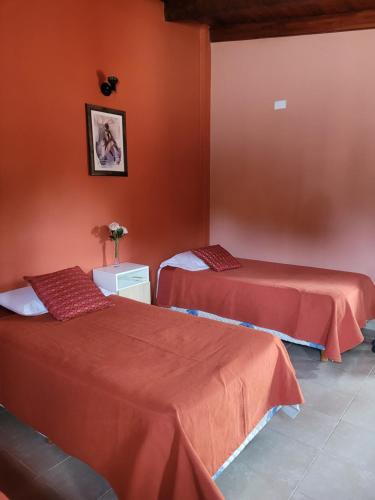 2 Betten in einem Zimmer mit orangefarbenen Wänden in der Unterkunft Alto Hermoso Apart in Cordoba