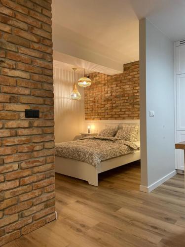 Un dormitorio con una pared de ladrillo y una cama en APARTAMENTY GUZIK, en Krosno