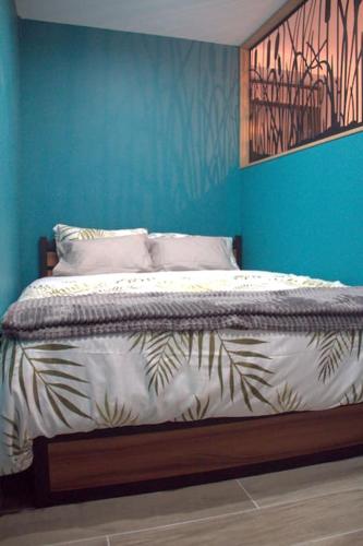 une chambre avec un lit avec un mur bleu dans l'établissement Logement cosy - proche du Prado, à Bourges