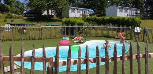 tres niños jugando en una piscina en un patio trasero en Stacaravan 6 persoons - Camping Le Soustran, en Neuvic