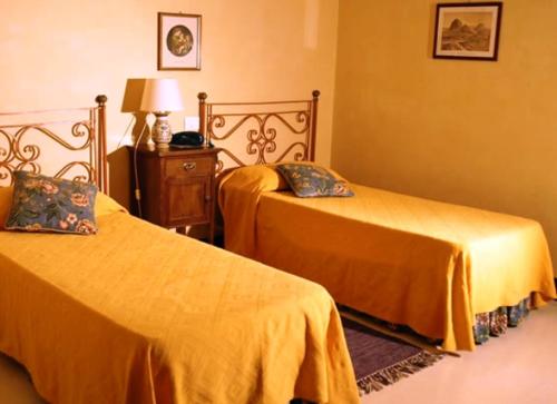 two beds in a hotel room with yellow sheets at Agriturismo Baglio Vecchio in Castelvetrano Selinunte