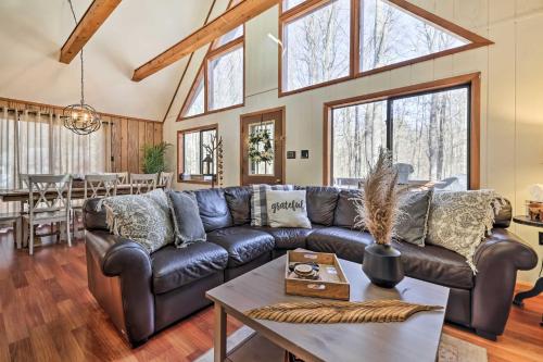 a living room with a leather couch and a table at Fire Pit and Grill Woodside Nest in Pocono Lake! in Pocono Lake
