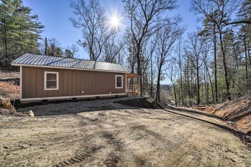 a tiny house on a dirt road in the woods at Modern Cabin with Fire Pit Less Than 3 Mi to Trails! in Pisgah Forest