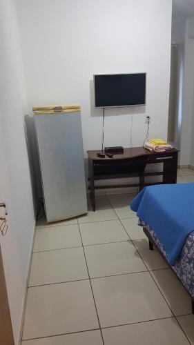 a room with a tv and a desk and a refrigerator at Hospedagem 20m da praia. in Itapema