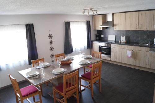 a dining room with a table and chairs and a kitchen at Ferienwohnungen Denk in Niederalteich