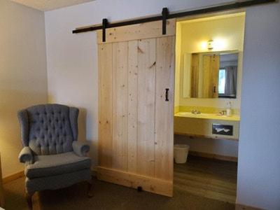 a bathroom with a wooden door with a chair and a sink at Old Montana Inn in Deer Lodge