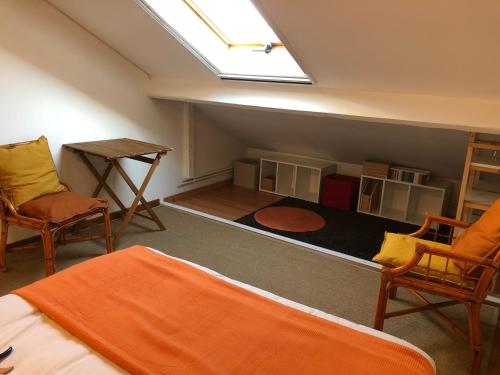 a attic room with a bed and two chairs and a table at 15 min - CDG et Paris in Aulnay-sous-Bois