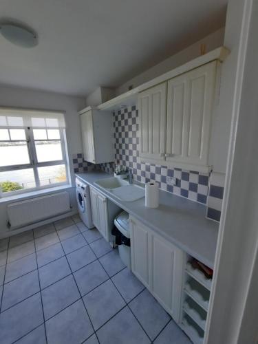 a kitchen with white cabinets and a sink and a window at River View Two Bed Room Luxury Apartment in Thamesmead