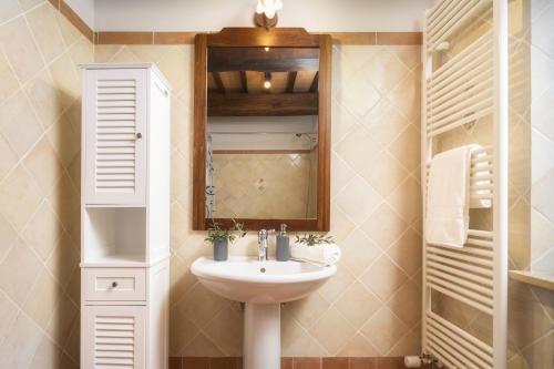 een badkamer met een wastafel en een spiegel bij Casa Ora d'Oro - PANORAMIC VIEWS / POOL / PRIVATE GARDEN in Trequanda